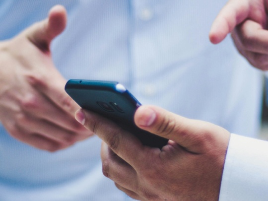 Photographie de 2 hommes autour d'un téléphone